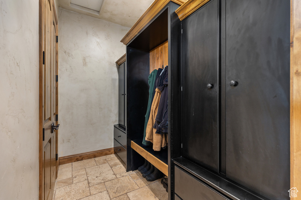 Mudroom featuring stone tile floors and attic access