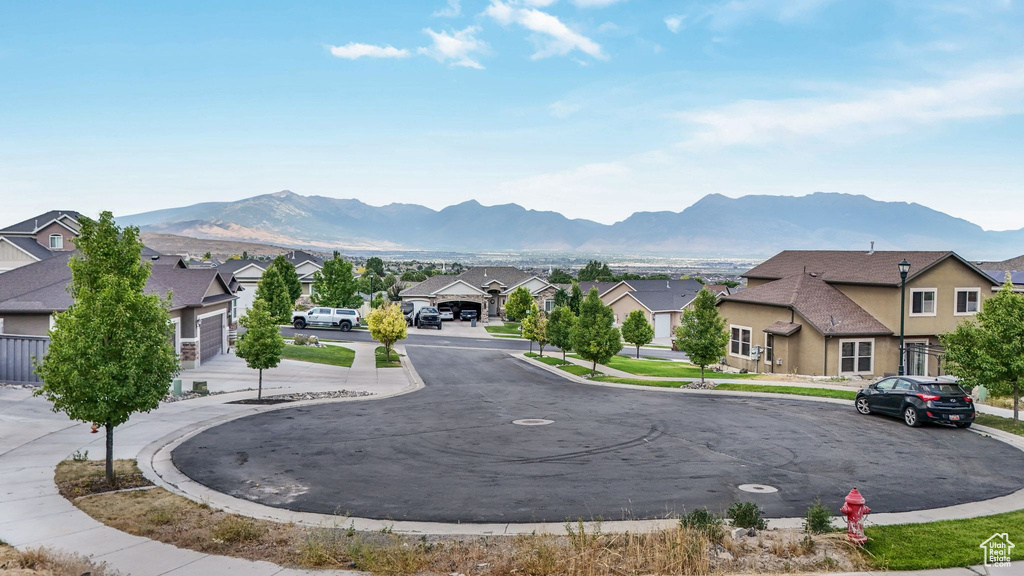 View of asphalt road featuring a residential view, a mountain view, curbs, and sidewalks