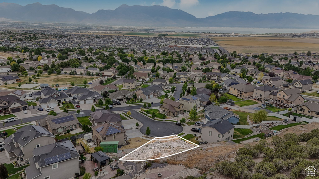Aerial view of property and surrounding area with a mountain backdrop, property boundaries highlighted, and nearby suburban area