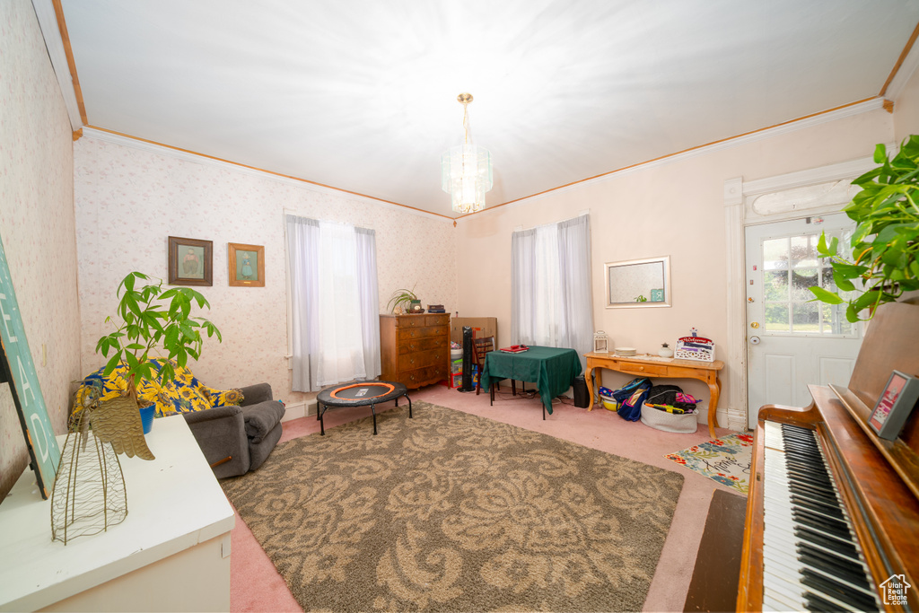 Carpeted living room featuring a chandelier, crown molding, and wallpapered walls