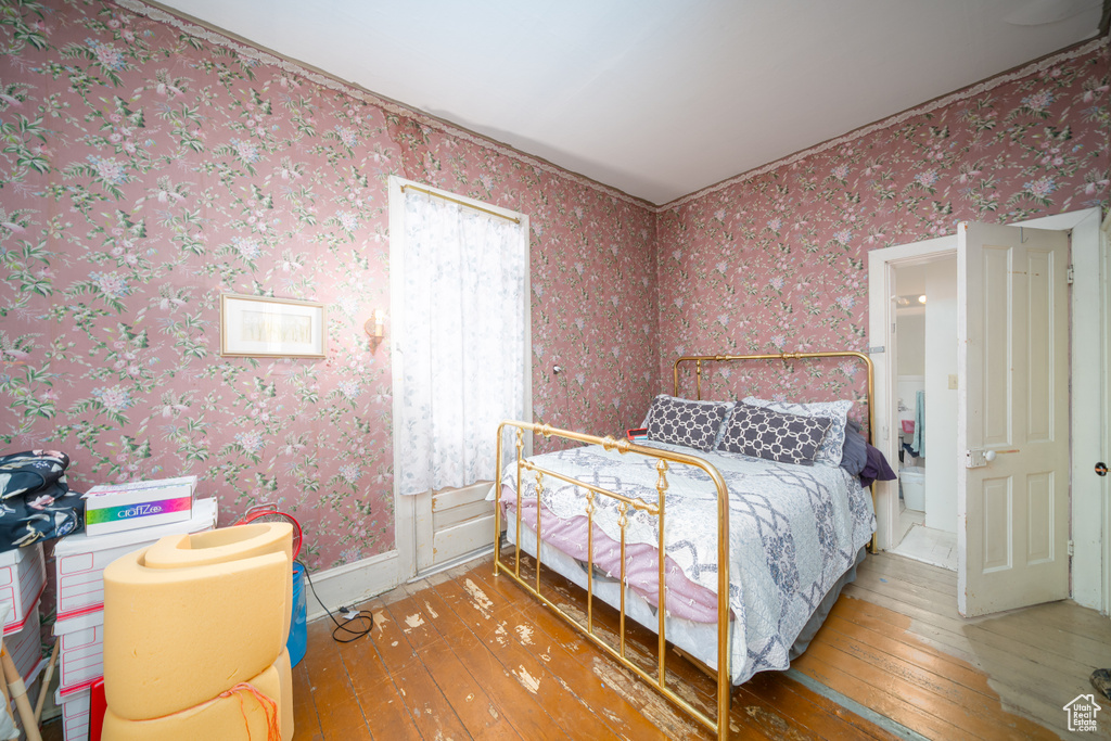 Bedroom featuring hardwood / wood-style floors and wallpapered walls