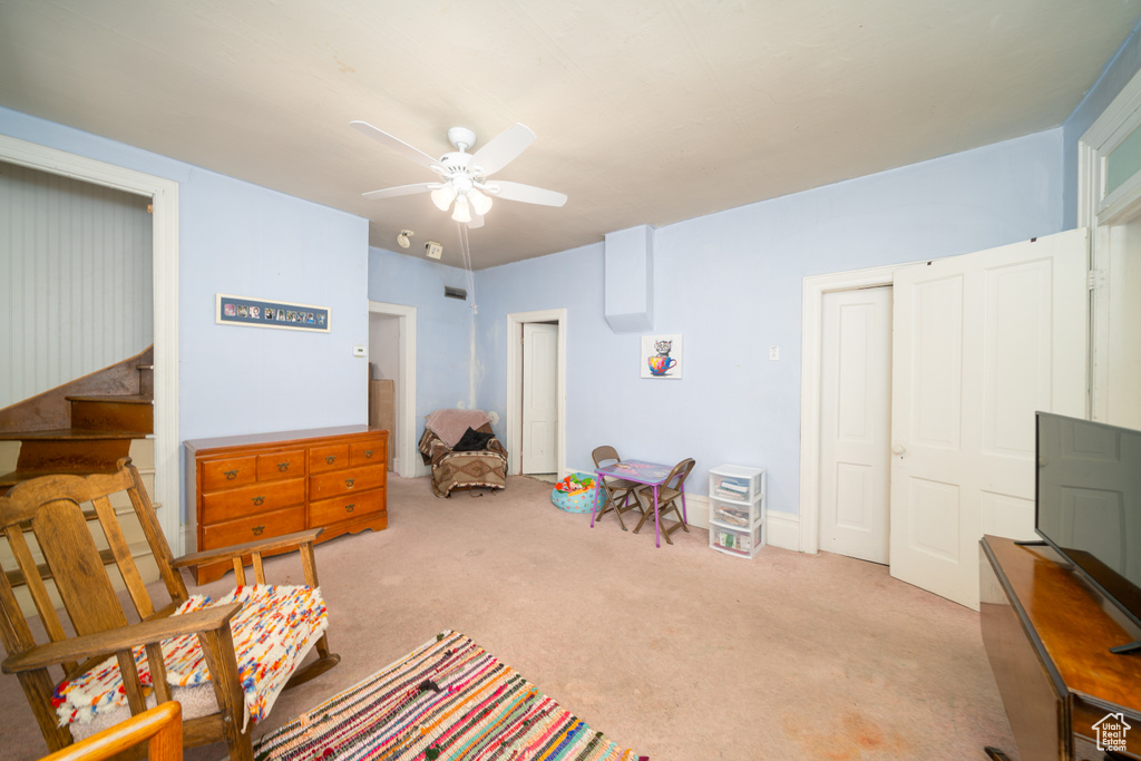 Living area with a ceiling fan and carpet flooring