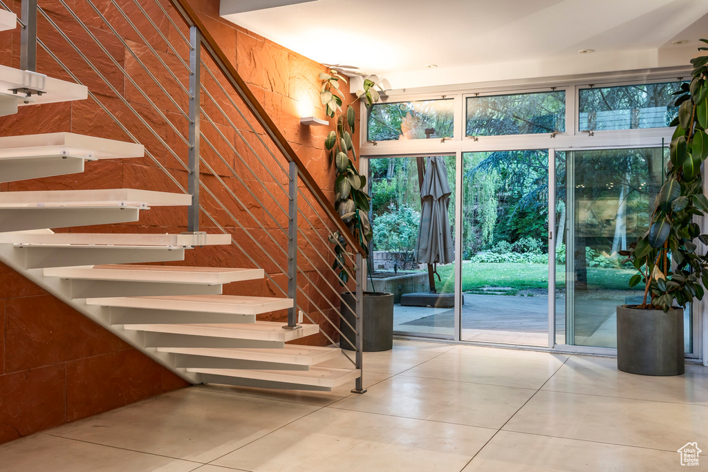 Stairs featuring healthy amount of natural light, tile patterned flooring, and wooden walls