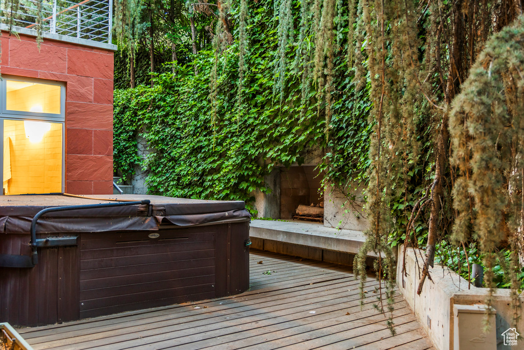 Wooden deck with a hot tub and an outdoor fireplace