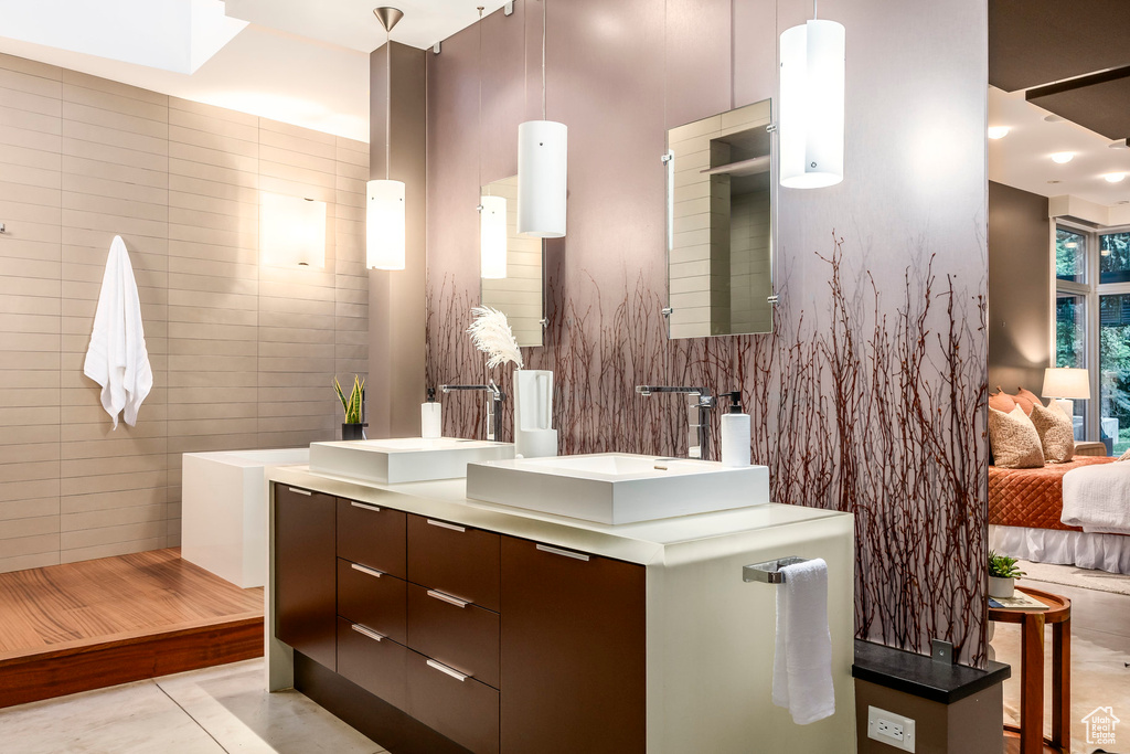 Full bathroom featuring double vanity, tile walls, tile patterned flooring, and ensuite bathroom