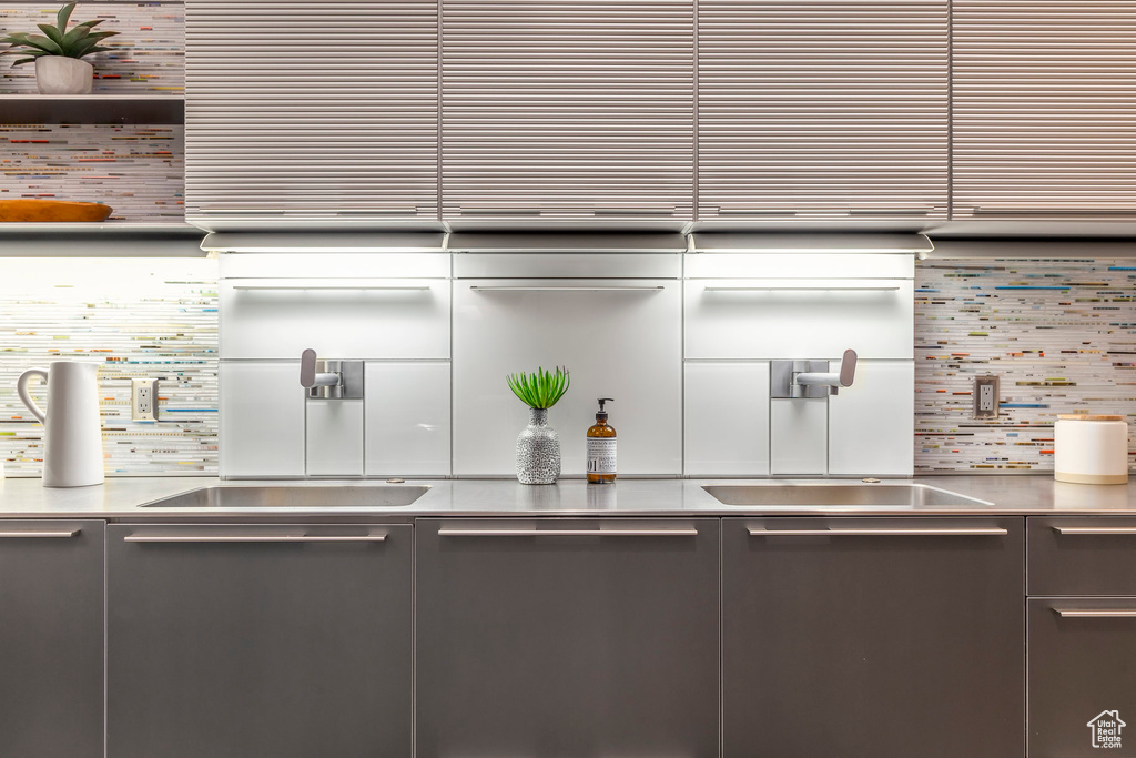 Kitchen featuring stainless steel counters, tasteful backsplash, dishwashing machine, and gray cabinets