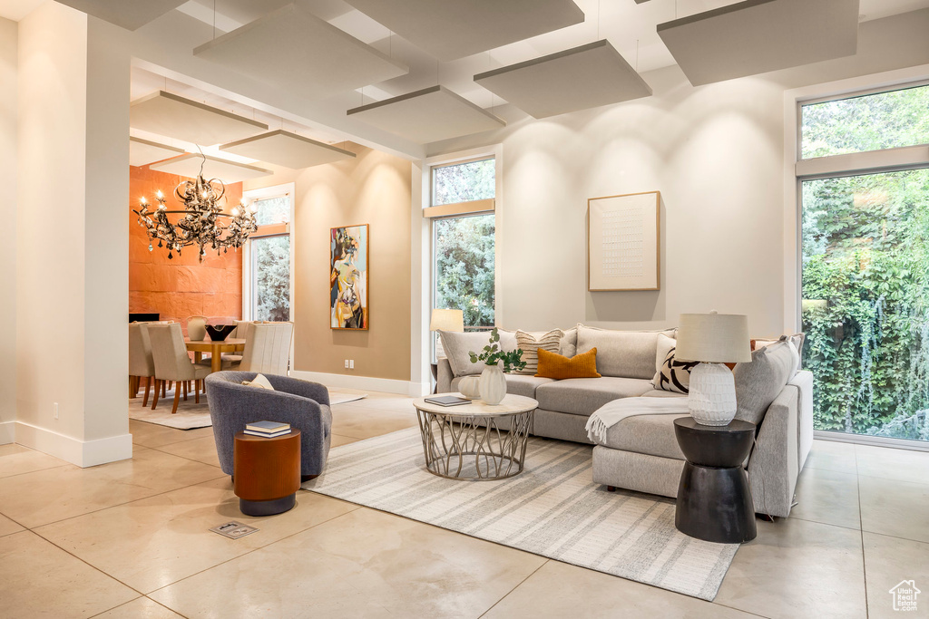 Living area with coffered ceiling, a chandelier, plenty of natural light, and tile patterned flooring