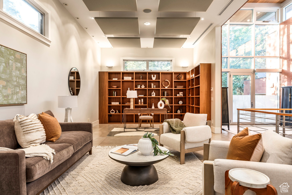 Tiled living room featuring a high ceiling, coffered ceiling, and plenty of natural light