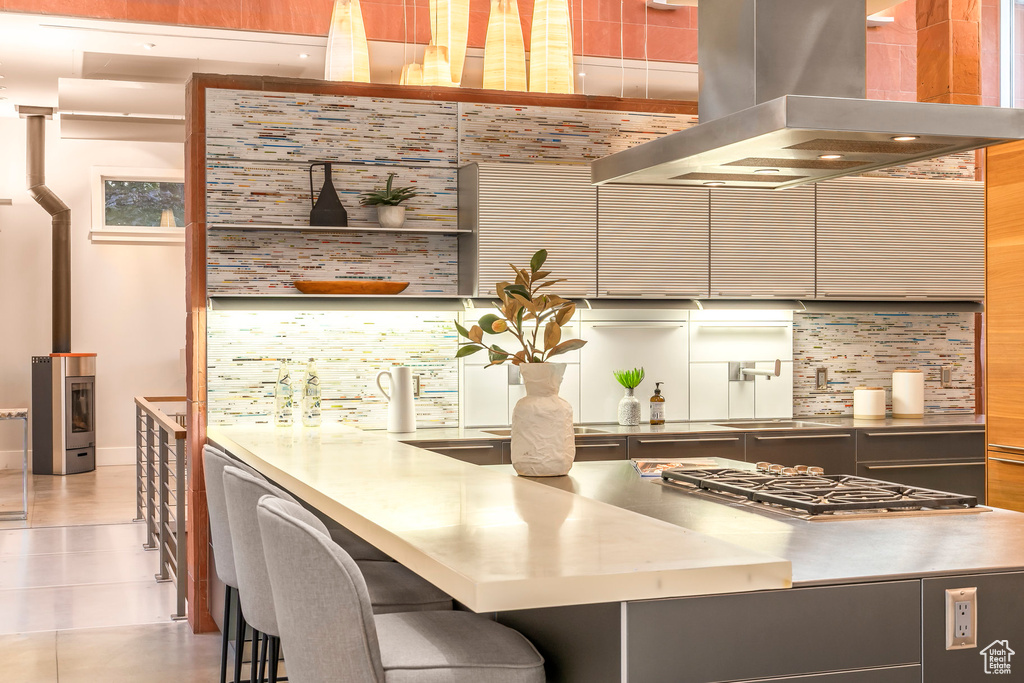 Kitchen with extractor fan, stainless steel countertops, stainless steel gas stovetop, backsplash, and light tile patterned floors