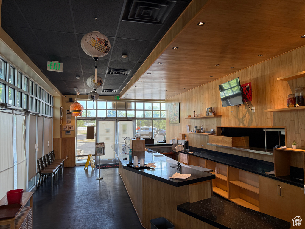 Kitchen with open shelves, wood walls, and dark countertops