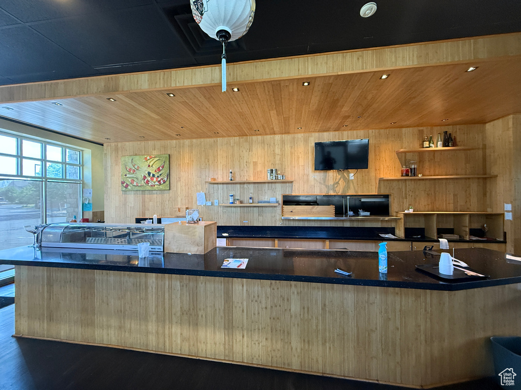 Kitchen with wood finished floors, wooden walls, wooden ceiling, open shelves, and dark stone countertops
