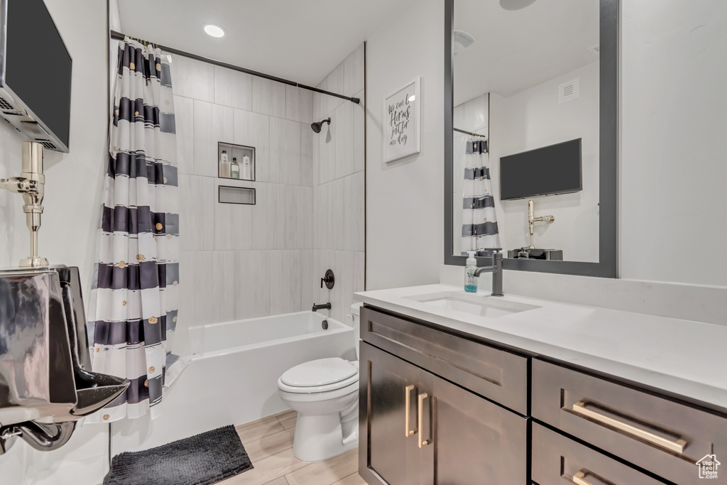 Bathroom with vanity, shower / bathtub combination with curtain, and wood finished floors