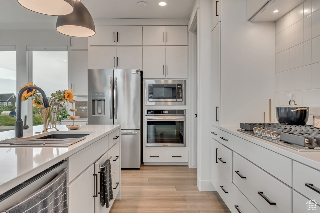 Kitchen featuring appliances with stainless steel finishes, light countertops, light wood-style flooring, tasteful backsplash, and recessed lighting