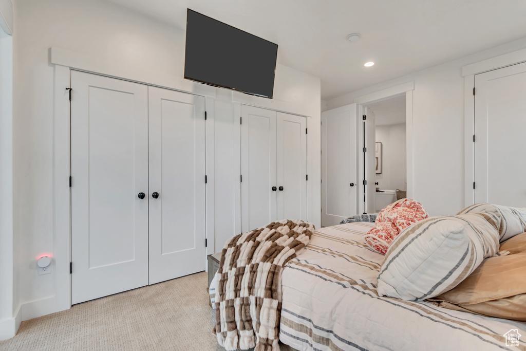 Bedroom with multiple closets, light colored carpet, and recessed lighting