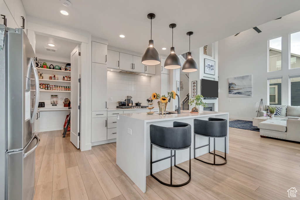 Kitchen featuring appliances with stainless steel finishes, light countertops, light wood-style floors, backsplash, and open floor plan