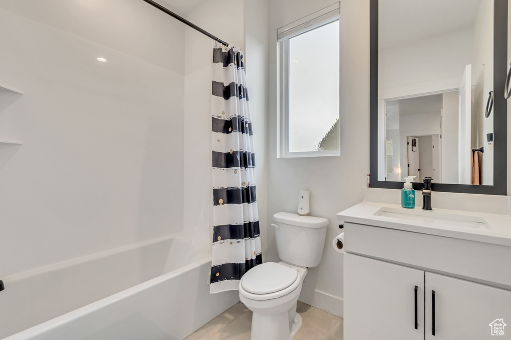 Bathroom with healthy amount of natural light, vanity, shower / bath combo, and tile patterned floors