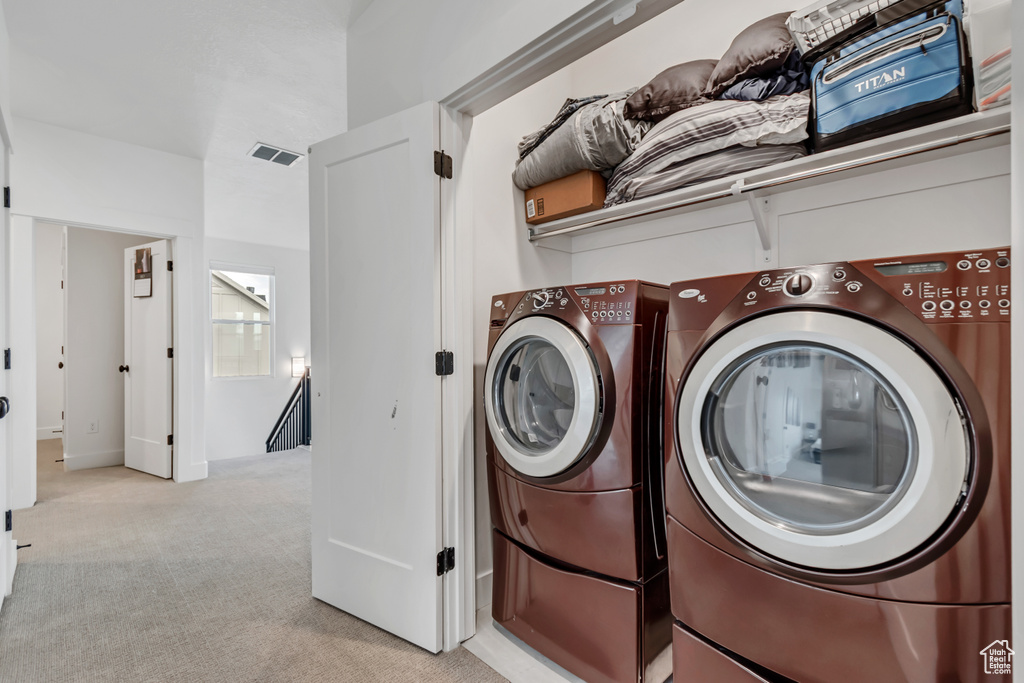 Laundry area with washing machine and clothes dryer and light colored carpet