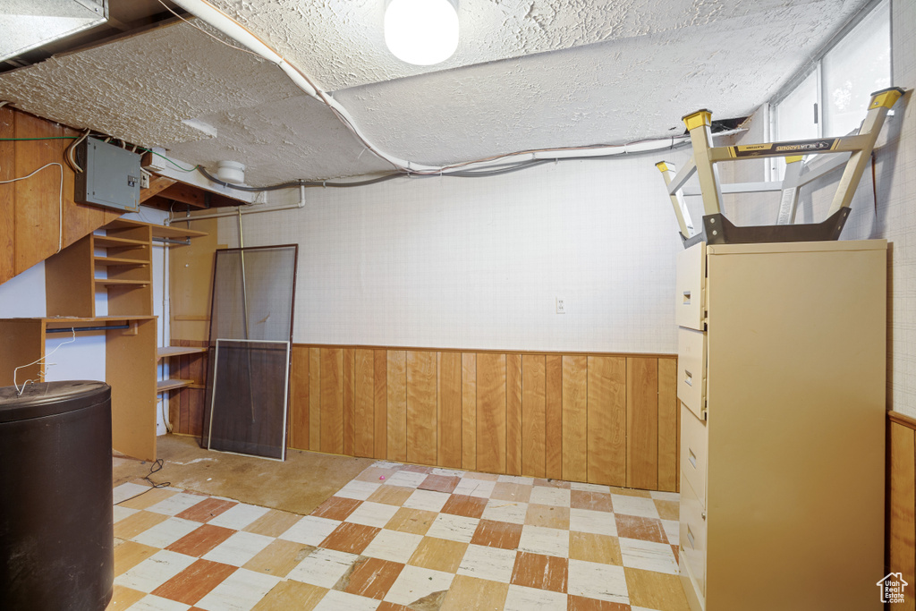 Below grade area featuring light flooring, wood walls, and a wainscoted wall