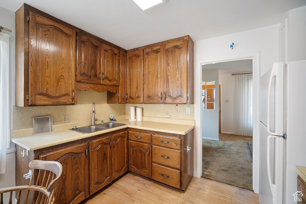 Kitchen featuring freestanding refrigerator, light countertops, and brown cabinetry