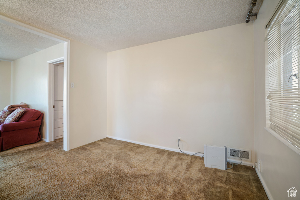 Carpeted empty room with a textured ceiling