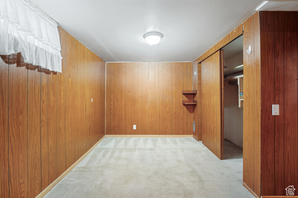 Carpeted spare room featuring wood walls