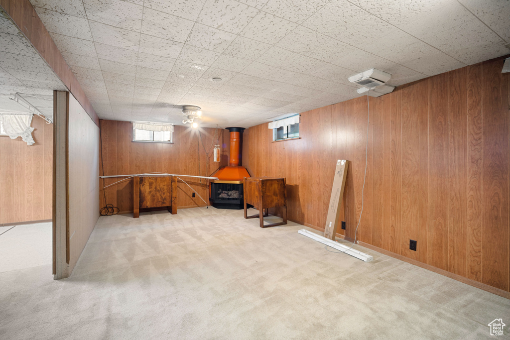 Below grade area featuring carpet floors, wooden walls, and a wood stove
