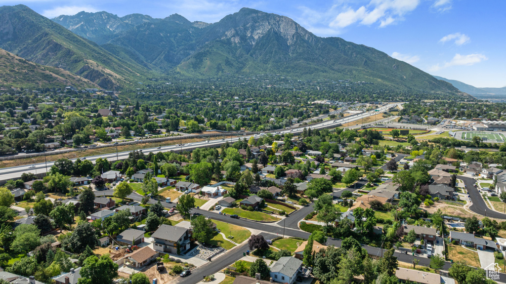 Aerial view of property and surrounding area featuring mountains and nearby suburban area