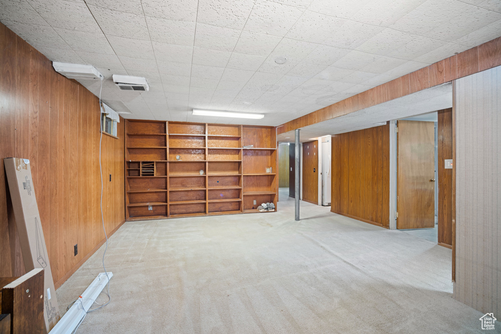 Finished basement featuring wooden walls, carpet floors, and built in shelves