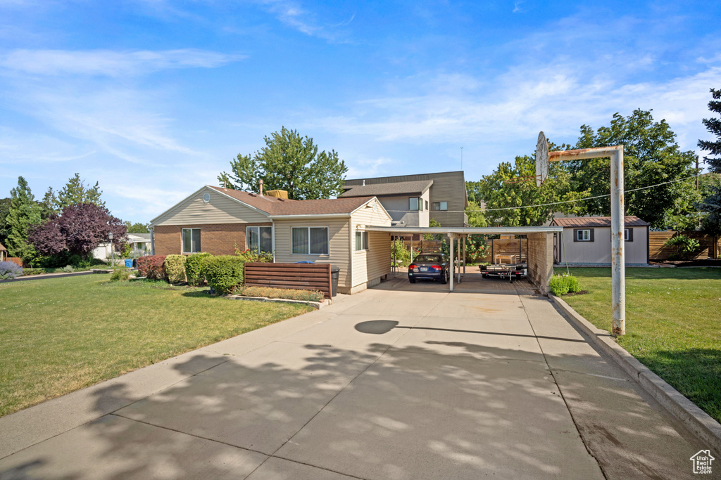 View of front of property with driveway, a front lawn, a carport, and an outdoor structure