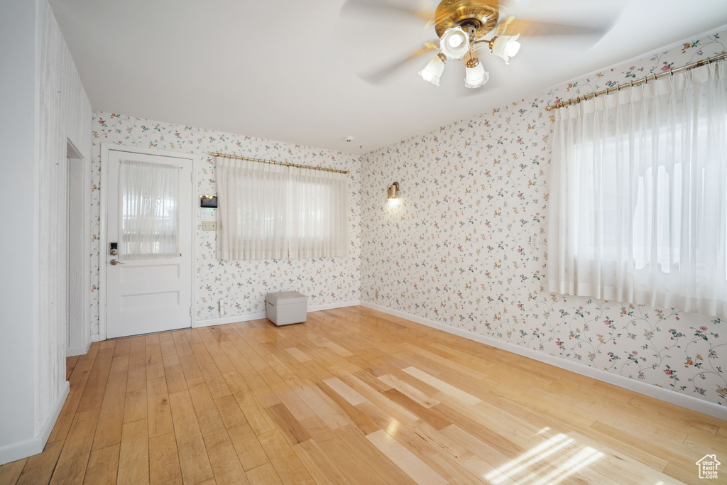 Unfurnished room featuring wallpapered walls, light wood-style flooring, and ceiling fan