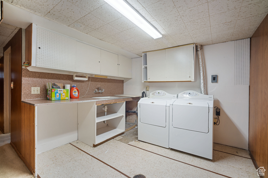 Laundry room with cabinet space, separate washer and dryer, and light floors