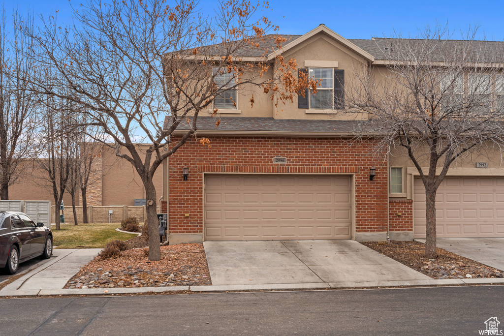 Traditional-style home with brick siding, a garage, concrete driveway, and stucco siding