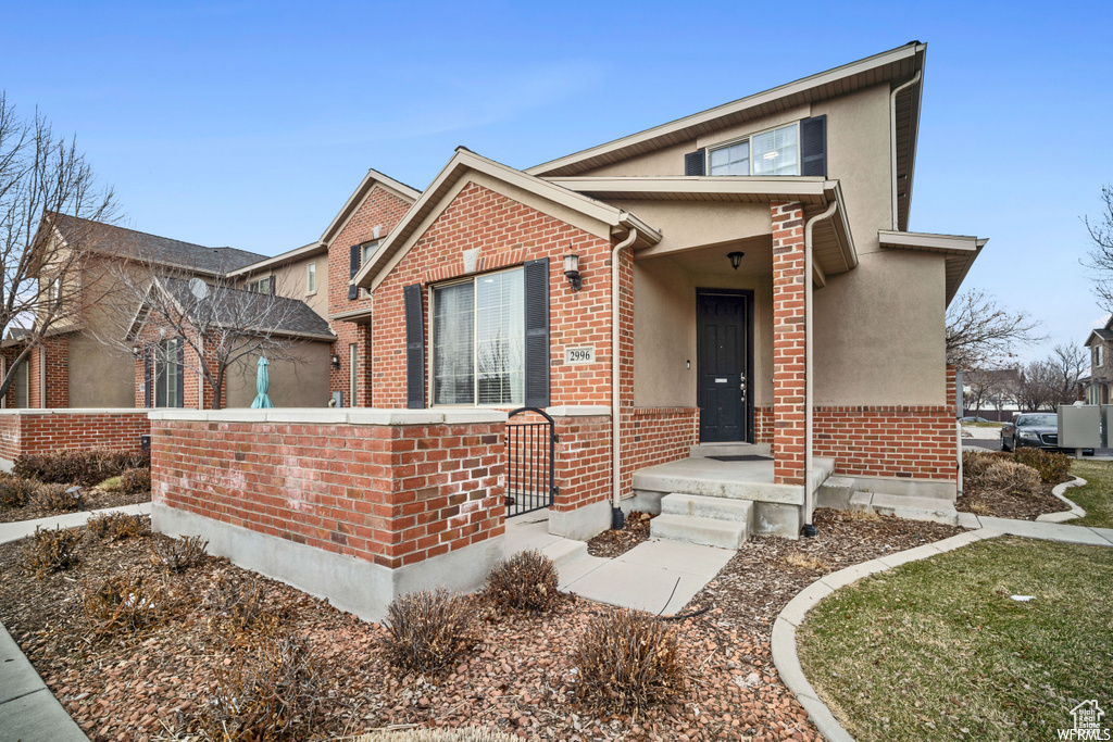 View of front facade featuring brick siding and stucco siding