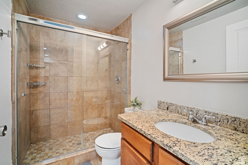 Bathroom featuring vanity, a textured ceiling, and a shower stall