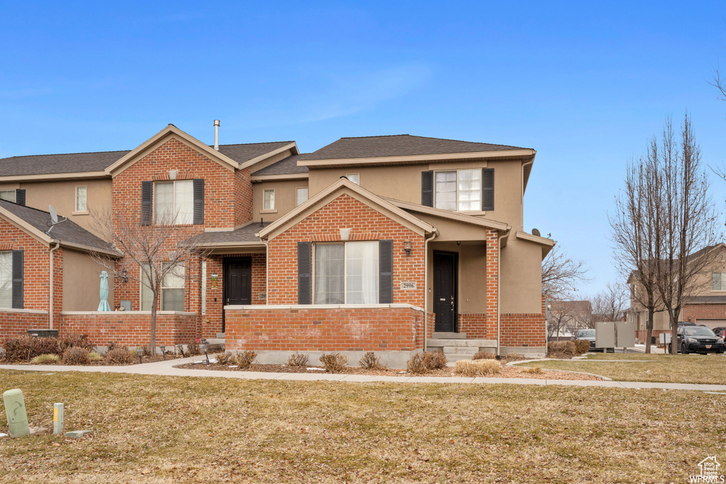 View of front of home with a front lawn, brick siding, and stucco siding