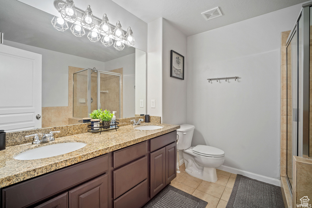 Full bathroom with a shower stall, double vanity, and tile patterned floors