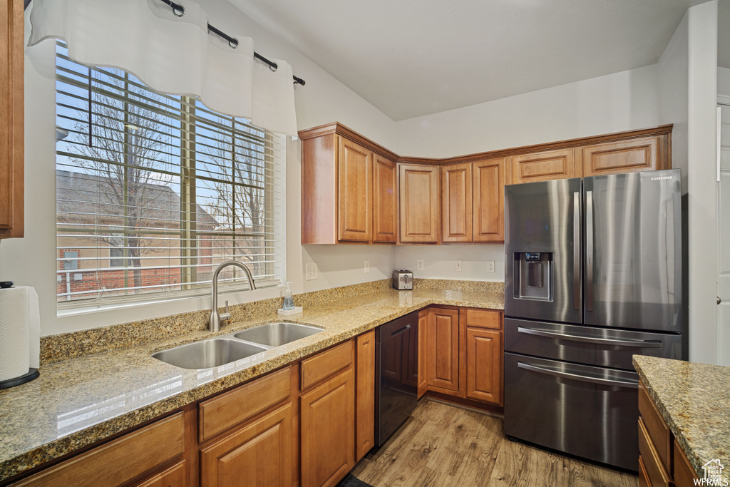 Kitchen featuring stainless steel fridge with ice dispenser, black dishwasher, healthy amount of natural light, and light stone countertops