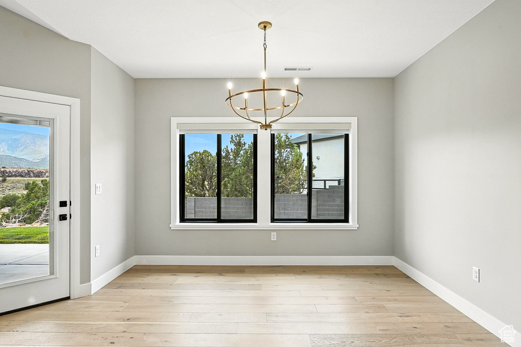 Unfurnished dining area featuring a chandelier and light wood-type flooring