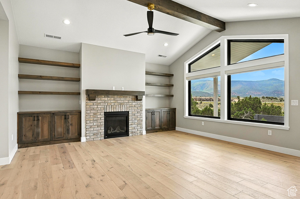 Unfurnished living room featuring light wood-style floors, a ceiling fan, a fireplace, recessed lighting, and a mountain view