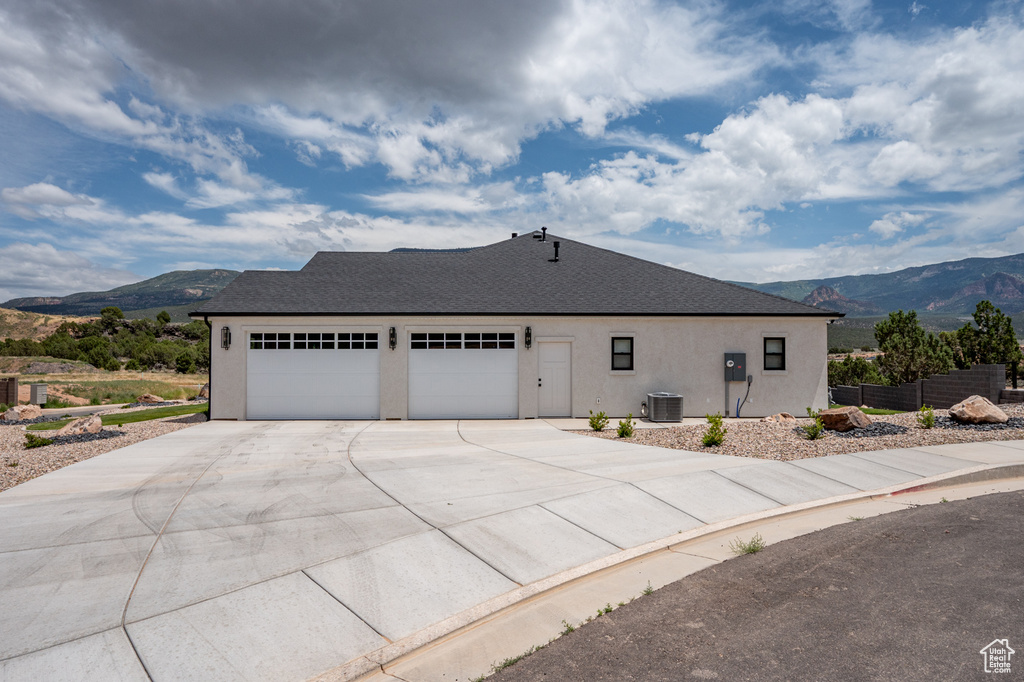 View of property exterior featuring a mountain view, driveway, an attached garage, and stucco siding