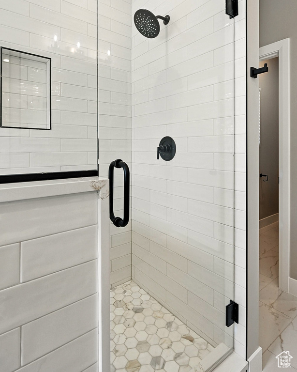 Full bath featuring marble finish floors and a shower stall