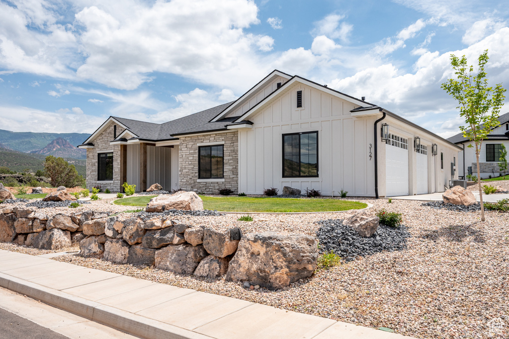 View of front of house featuring board and batten siding, a garage, and stone siding