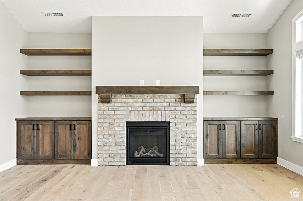 Unfurnished living room with wood finished floors, plenty of natural light, and a brick fireplace