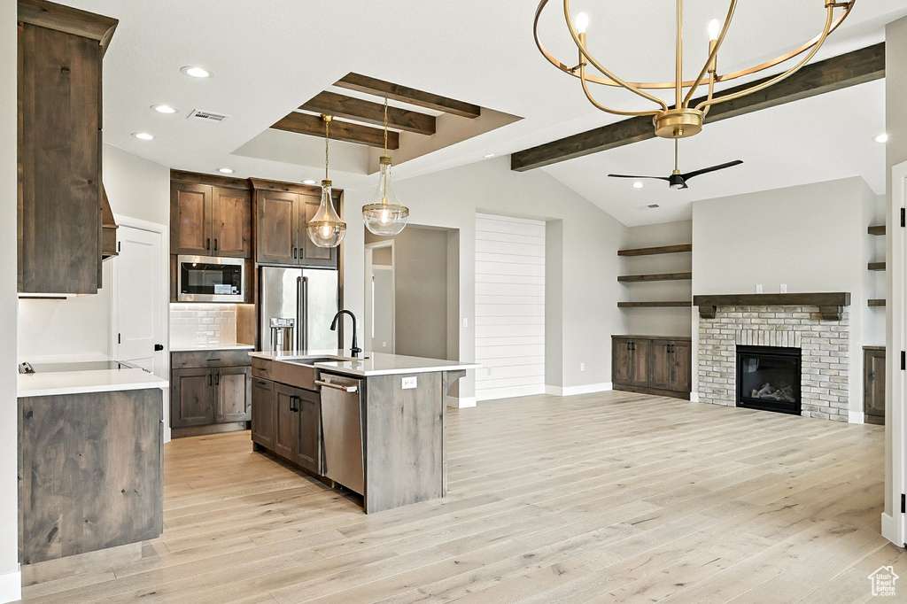 Kitchen with stainless steel appliances, decorative backsplash, dark brown cabinets, light countertops, and recessed lighting