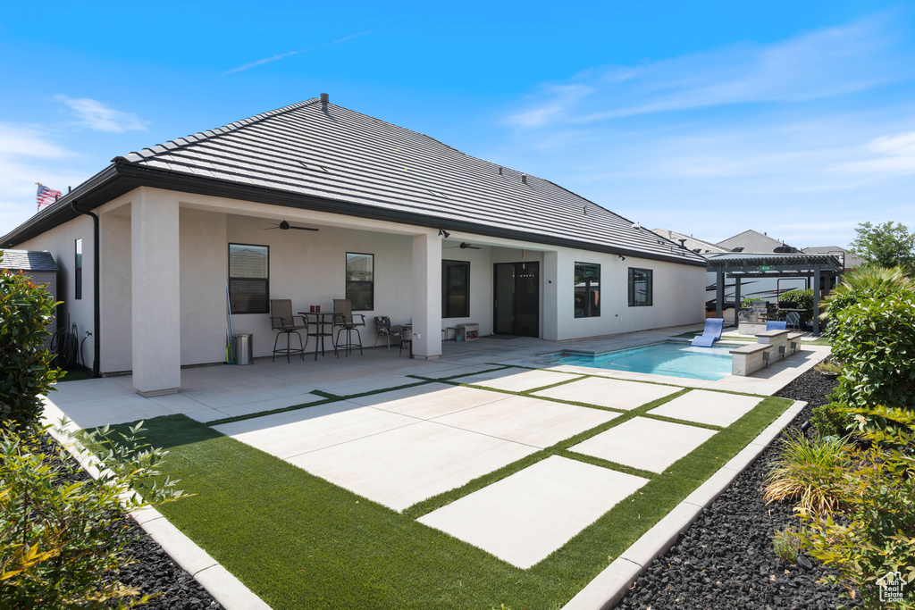 Back of property with ceiling fan, a pergola, stucco siding, and a patio