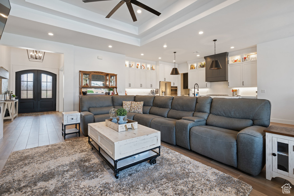 Living area with wood finished floors, ceiling fan, a chandelier, recessed lighting, and french doors