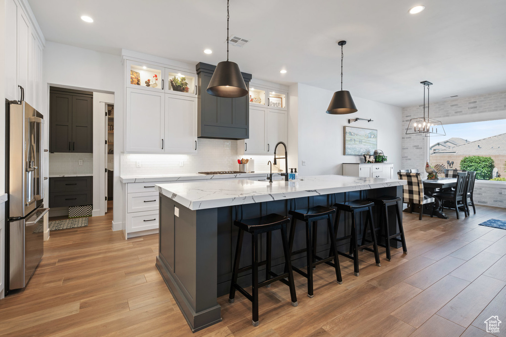 Kitchen with high end refrigerator, light wood-type flooring, tasteful backsplash, and recessed lighting