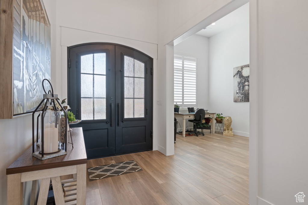 Entrance foyer featuring arched walkways, french doors, and wood finished floors