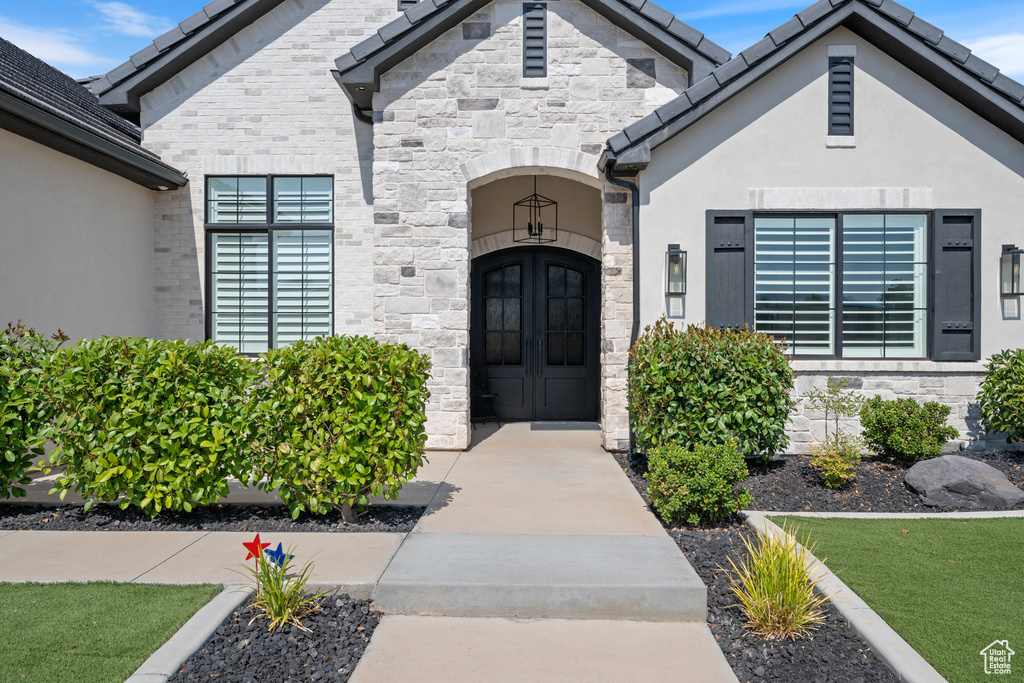 Property entrance with stone siding, stucco siding, and french doors