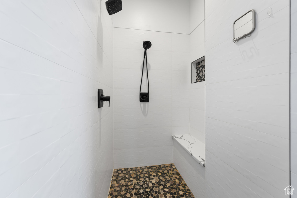 Full bathroom featuring tiled shower and tile walls